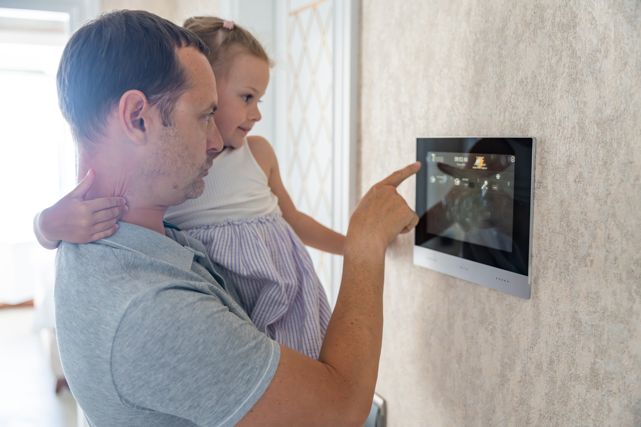 Modern home, smart control panel, man and daughter interact closely, natural morning light, documentary style, two people.