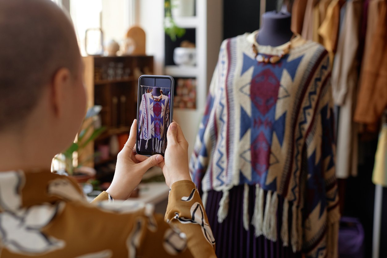 Boutique interior, fringed patterned sweater on mannequin, mid-frame, daytime light, editorial travel photo, one person.