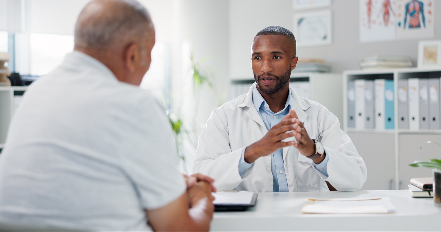 Exam room, doctor and older patient, desk with papers, indoor daylight, documentary style, two people present.
