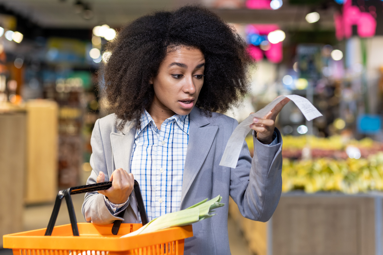 Grocery store, woman with basket and long receipt center frame, daytime bright, documentary style, single person.