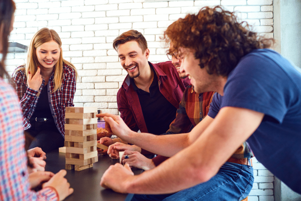 Bright room, Jenga game in progress, wooden table, natural light filters in, editorial travel photo, young adults gathered.