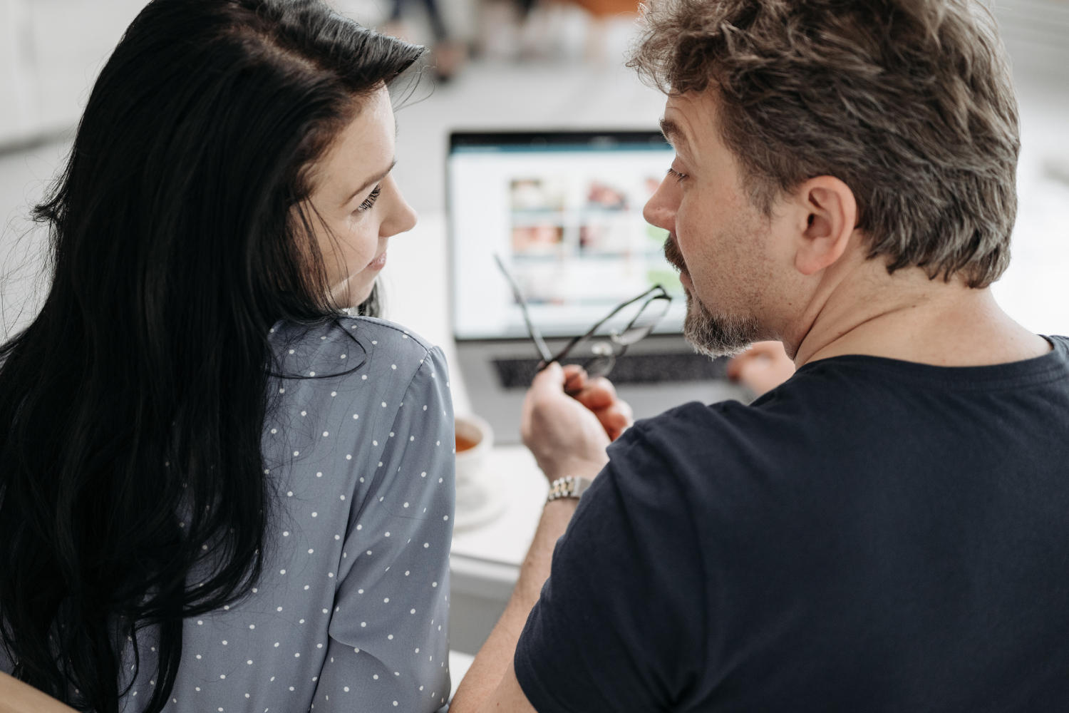 Office interior, laptop-centered scene, intimate two-shot composition, soft afternoon light, editorial travel photo, two people.