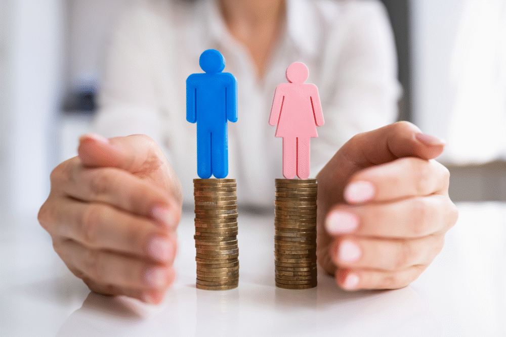 Desk scene, coin stacks, gender icon toppers, central focus, natural light, editorial concept photo, single person present.