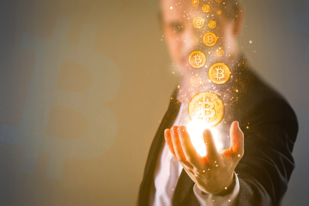 Office, suited person with hand outstretched, glowing Bitcoin icons above, diffused light, editorial photo, single person present.